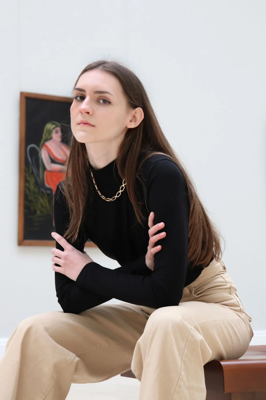 Schwarzes Oberteil und beige Hose in einer Kunstgalerie.