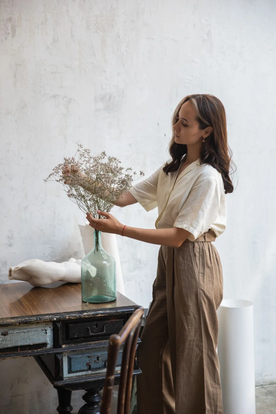 Locker geschnittene helle Bluse und weite braune Hose.