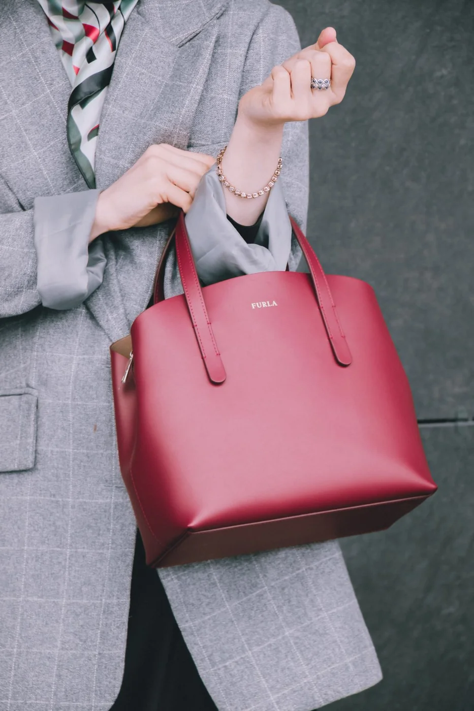 Rote Handtasche vor einem grauen Blazer.