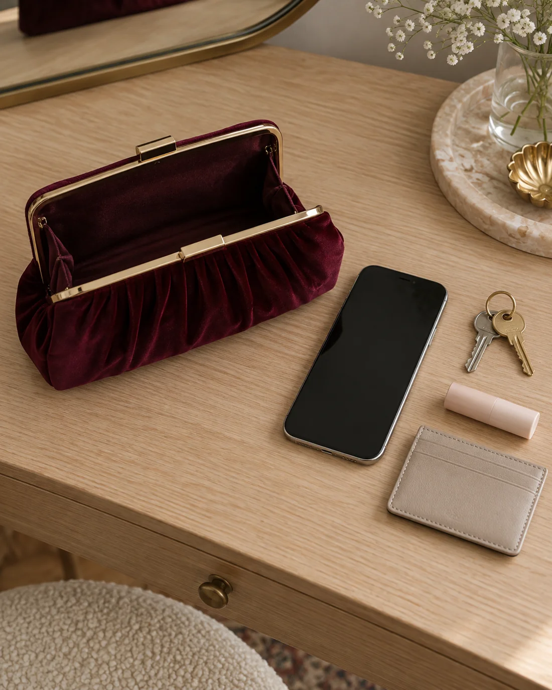Kleine Abendtasche neben Telefon, Schlüsseln und Kartenetui.