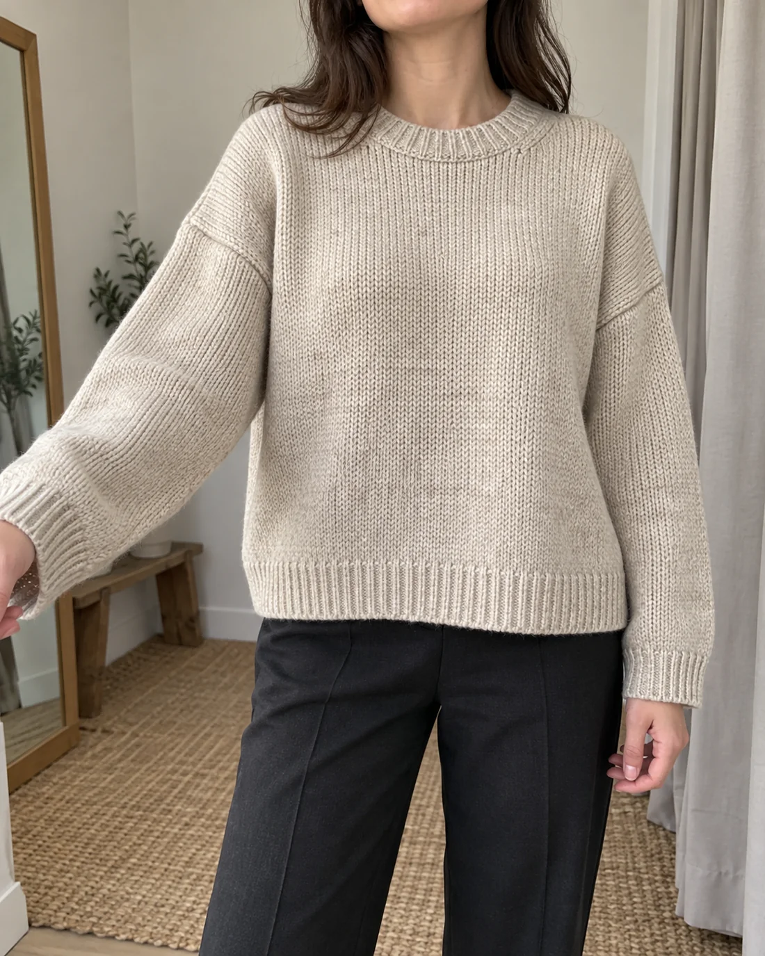 Locker geschnittener heller Strickpullover mit überschnittenen Schultern und sichtbaren Ärmelbündchen.